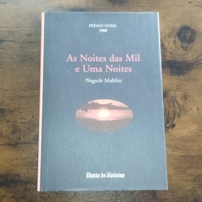 Livro As Noites das Mil e Uma Noites sobre mesa de madeira