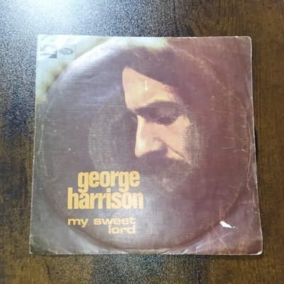 Capa de vinil vintage com rosto masculino e texto George Harrison My Sweet Lord.