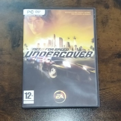 Caixa do jogo PC Need for Speed Undercover com capa amarela e preta mostrando carros e edifícios