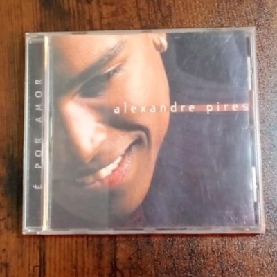 Capa de CD com rosto sorridente e textos 'alexandre pires' e 'É POR AMOR'.