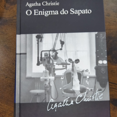 Livro de capa dura O Enigma do Sapato de Agatha Christie com imagem a preto e branco de equipamento médico.