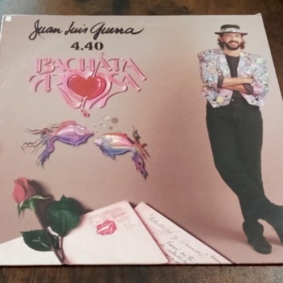 Capa de vinil Juan Luis Guerra Bachata Rosa com homem vestido formal e elementos românticos