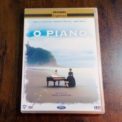 Capa de DVD do filme O Piano com imagem de piano numa praia