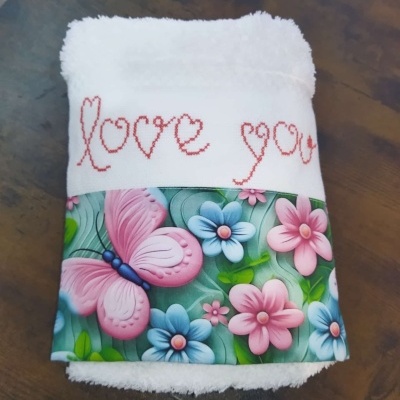 Toalha branca com bordado love you e faixa decorativa de borboleta e flores