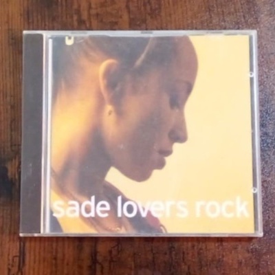 CD 'sade lovers rock' com capa de mulher em perfil em fundo amarelo