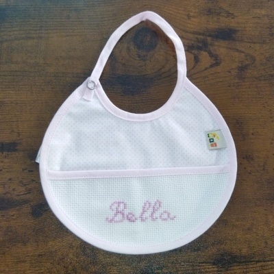 Babete para bebé branco com rosa claro e nome 'Bella' bordado em ponto cruz