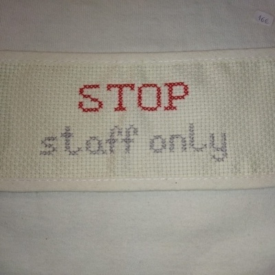 Pano branco bordado com STOP em vermelho e staff only em cinzento, etiqueta de preço 16€.