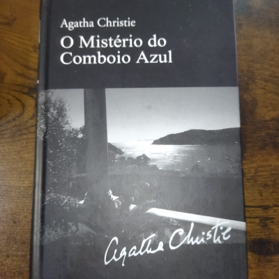 Capa de livro em preto e branco O Mistério do Comboio Azul de Agatha Christie com imagem de paisagem costeira