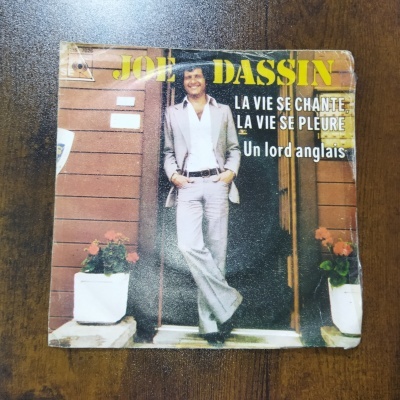 Capa de disco de vinil com homem em fato cinzento e texto promocional