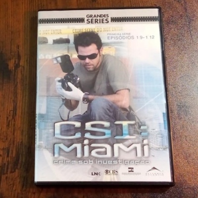 DVD da série CSI: Miami com capa de homem com câmara e texto de série e episódios
