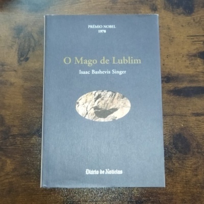 Livro 'O Mago de Lublim' capa cinzenta com texto e ilustração oval