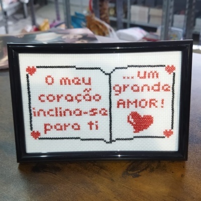 Quadro de ponto cruz com texto em português e corações vermelhos