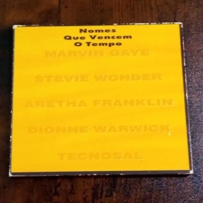 Capa amarela de CD ou vinil com letras pretas e amarelas com nomes de artistas famosos