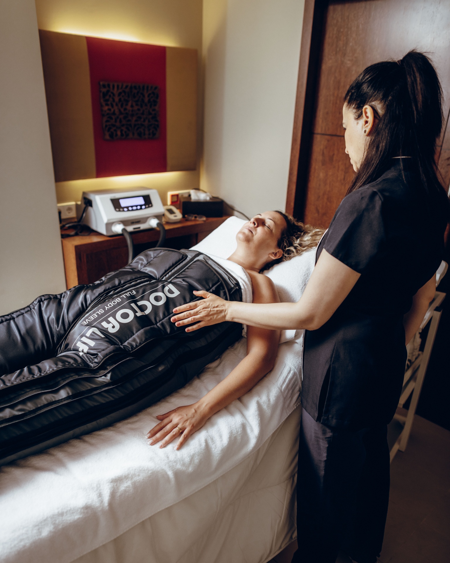 Pressoterapia avançada (30 min) Mulher deitada com fato insuflável Doctor Life e terapeuta ao lado