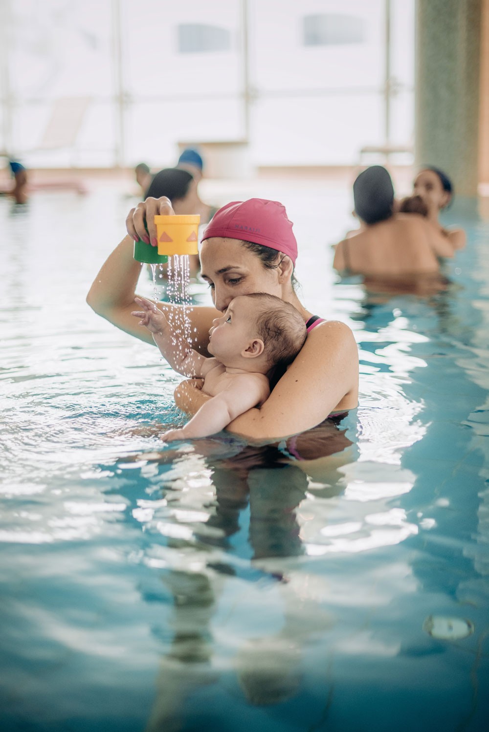 Aquababy Hidroterapia Pais&Bebés - Sessão 50-min. Mulher na piscina a segurar bebé com copos de plástico a verter água