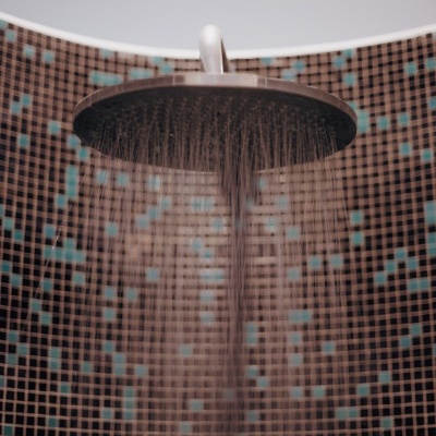 Chuveiro redondo de metal com água a cair e parede com mosaicos castanhos e azuis