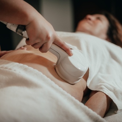 Dispositivo branco para tratamento corporal num abdómen coberto por toalha branca