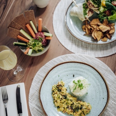 Mesa posta com comida variada em pratos e taça, guardanapo com texto PALÁCIO ESTORIL Organic Caffè.