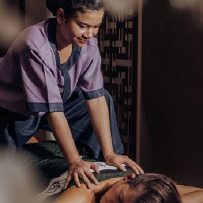 Massagista a dar massagem a cliente deitada numa mesa em ambiente interior