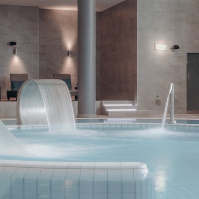 Piscina interior moderna com borda de ladrilhos brancos e decoração em fundo cinza