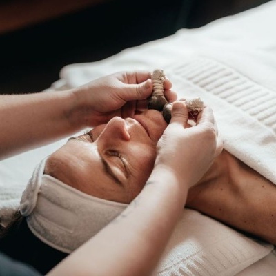 Pessoa a receber massagem facial com pedras sobre toalha branca