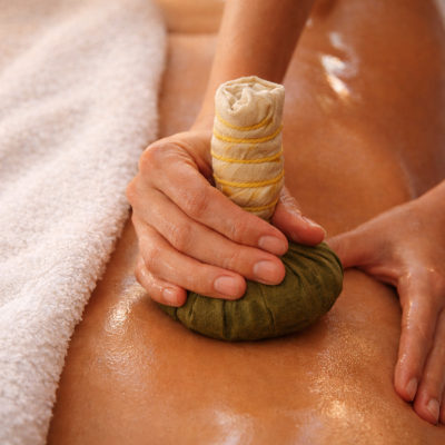 Massagem corporal com saco de ervas e toalha branca ao lado