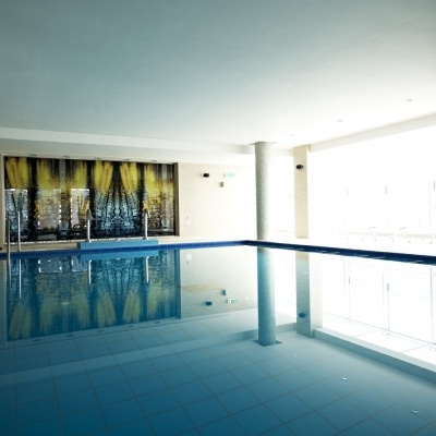 Piscina interior retangular com azulejos azuis e colunas brancas