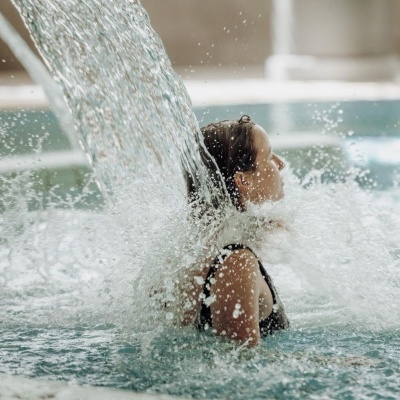 Mulher em piscina sob queda de água