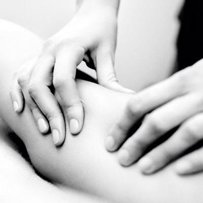 Mãos humanas a pressionar pele de uma perna num ambiente desfocado