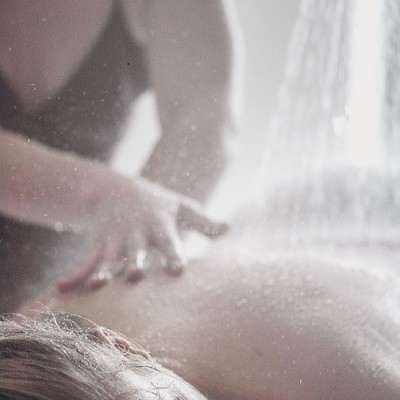 Pessoa a receber massagem nas costas com aplicação de água em ambiente tranquilo