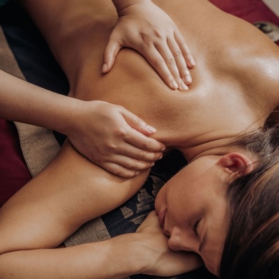 Pessoa deitada de bruços a receber massagem nas costas num tapete colorido