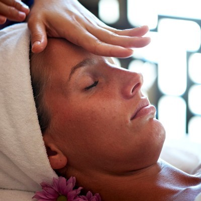 Pessoa a receber massagem facial com toalha branca na cabeça