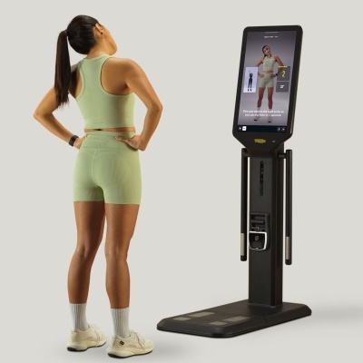 Mulher a fazer exercício de pescoço com roupa de treino verde claro em frente a dispositivo digital com ecrã tátil