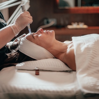 Tratamento facial com dispositivo aplicado na testa de mulher deitada