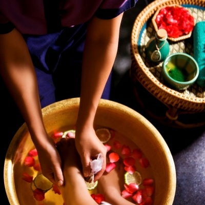 Massagem nos pés com bacia com pétalas e limão e mesa com acessórios de spa