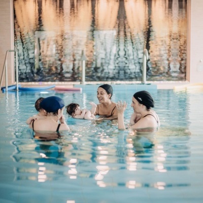 Piscina interior com três mulheres e dois bebés na água
