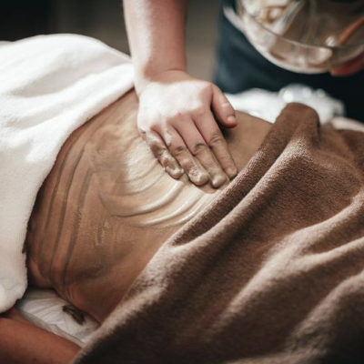 Massagem com creme castanho nas costas de uma pessoa