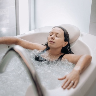 Mulher relaxando em banheira de hidromassagem branca com água com bolhas