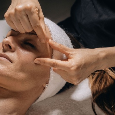 Mulher a receber massagem facial com faixa branca na cabeça