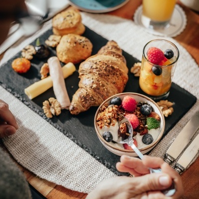 Pequeno-almoço com croissant, iogurte com granola e frutos vermelhos, queijos e fiambre
