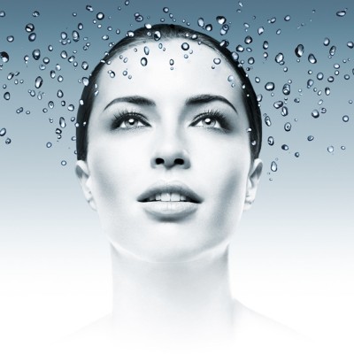 Rosto feminino em preto e branco com gotas de água suspensas acima da cabeça