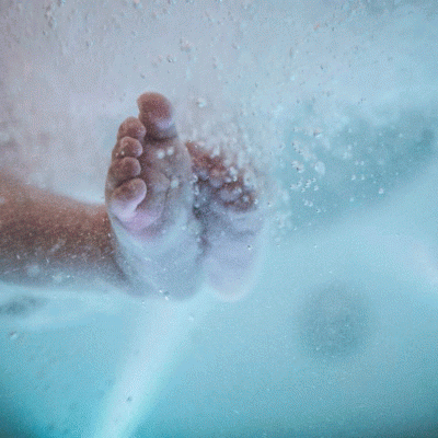Pés de bebé vistos através de água com bolhas