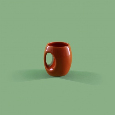 Caneca castanha com pega circular vazada sobre fundo verde