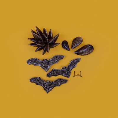 Peças decorativas metálicas escuras sobre fundo laranja