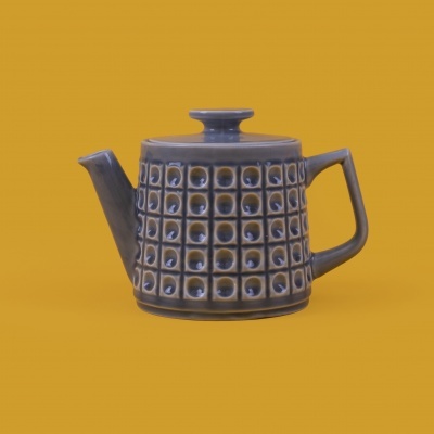 Bule de chá cinzento com padrão geométrico em relevo sobre fundo amarelo