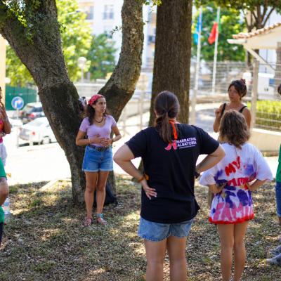 Grupo de jovens em atividade ao ar livre com t-shirts verdes, pretas e branca manchada de tinta colorida