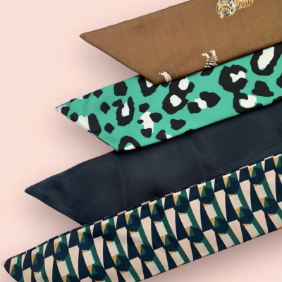 Quatro almofadas retangulares com diferentes padrões e cores alinhadas em superfície rosa