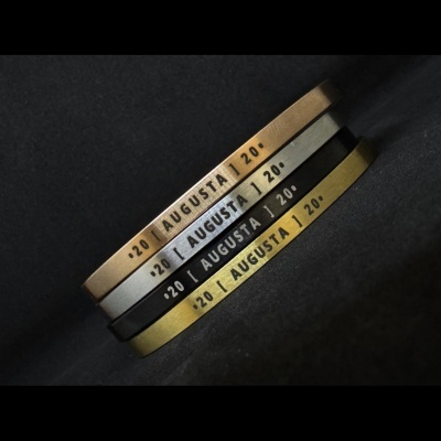 Pulseiras metálicas com texto AUGUSTA gravado, em várias cores.