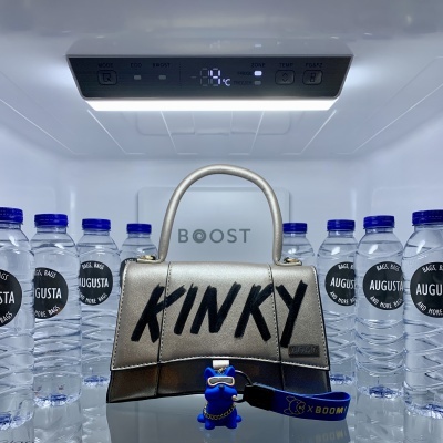 Mala metálica pequena com palavra 'KINKY' dentro de frigorífico entre garrafas de água 'AGUSTA'