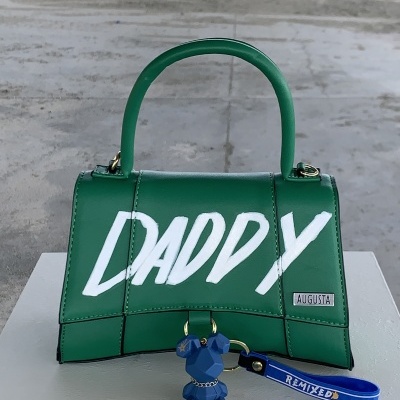 Mala de mão verde com texto DADDY e chaveiro azul de cão